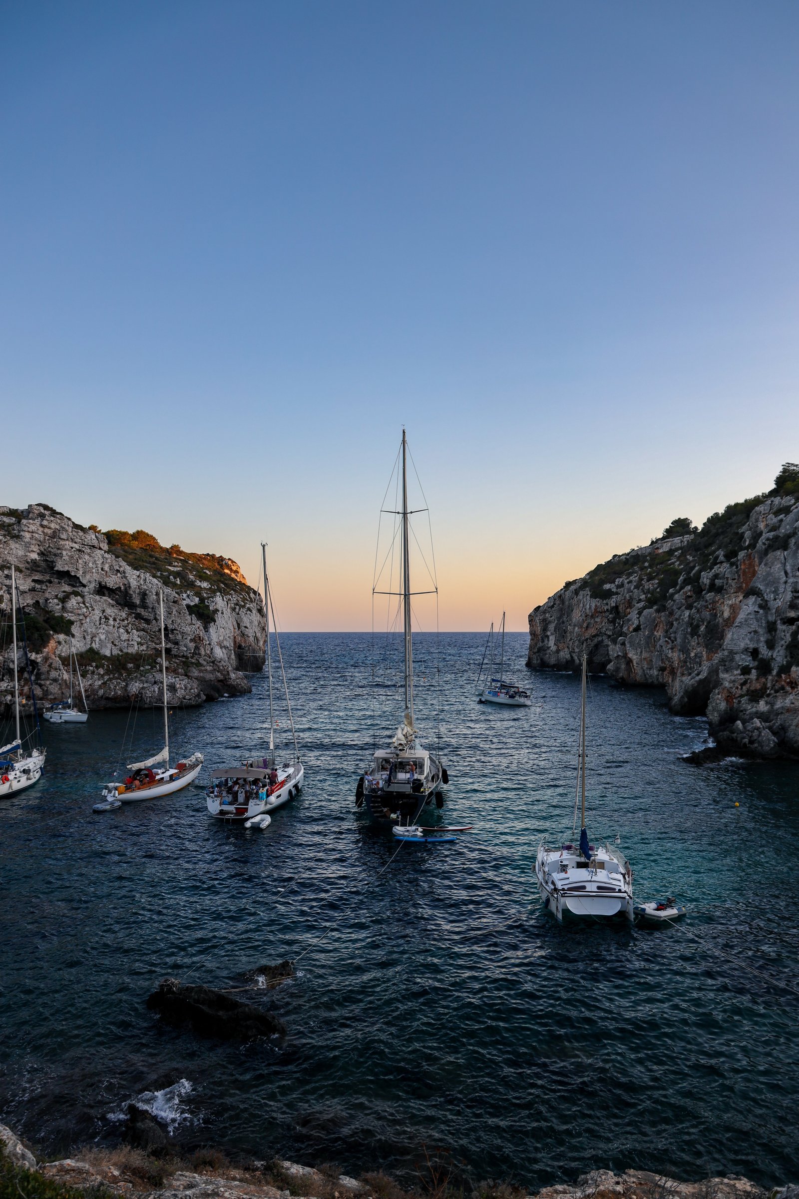 Yachts anchored in a quiet cove at dusk